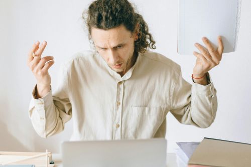 A frustrated man at his desk showing signs of exhaustion and stress in an office setting.