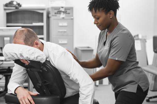 Crop anonymous medical specialist rubbing shoulders of male client lying on couch in medical salon